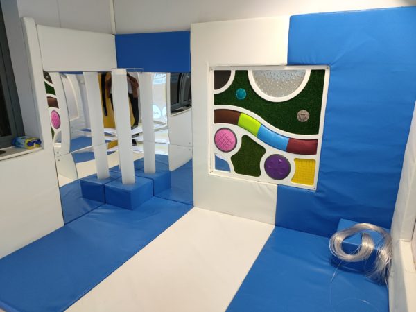 Multi sensory Room with soft padded walls and floor, containing a bubble tube and tactile panel