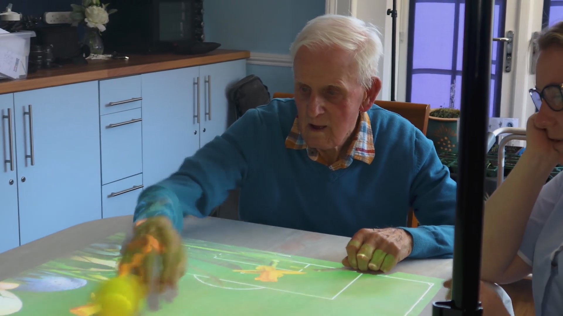 Care home resident improving their wellbeing by engaging in tennis using the Wellbeing suite interactive projector. Demonstrating creativity and self-expression. A clear indication of improvements in Social interaction, Emotional well-being, and cognitive stimulation