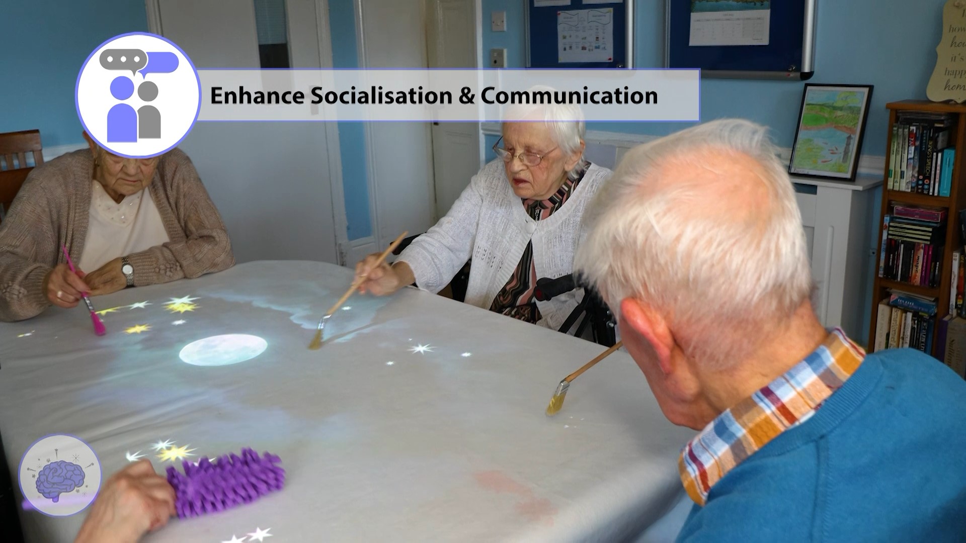 Care home residents taking part in a group activity and discussing the calming stars that appear whilst using the Wellbeing suite interactive projector on a table with the included long reach paintbrush accessory