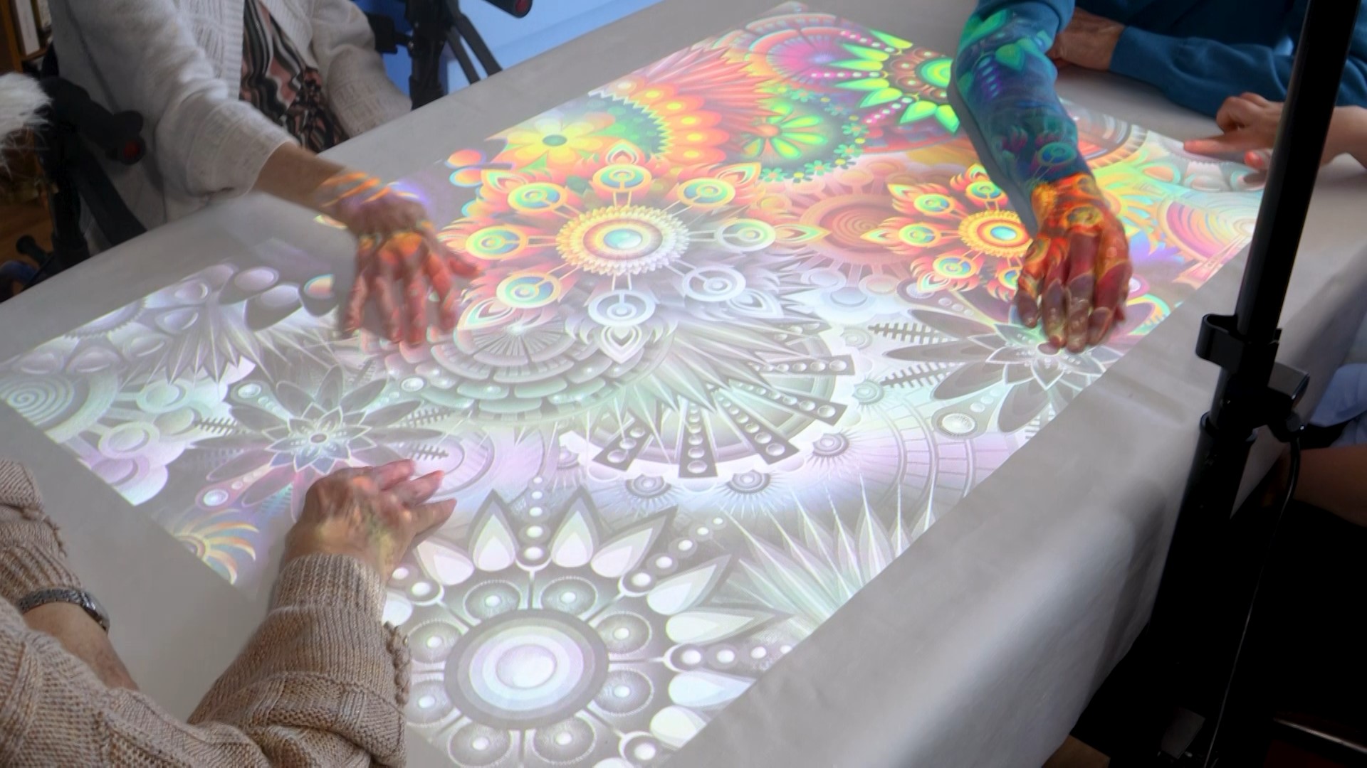 Care home residents taking part in a group activity and unleashing there creativity by colouring in the vibrant images with this art / music activity whilst using the Wellbeing suite interactive projector on a table