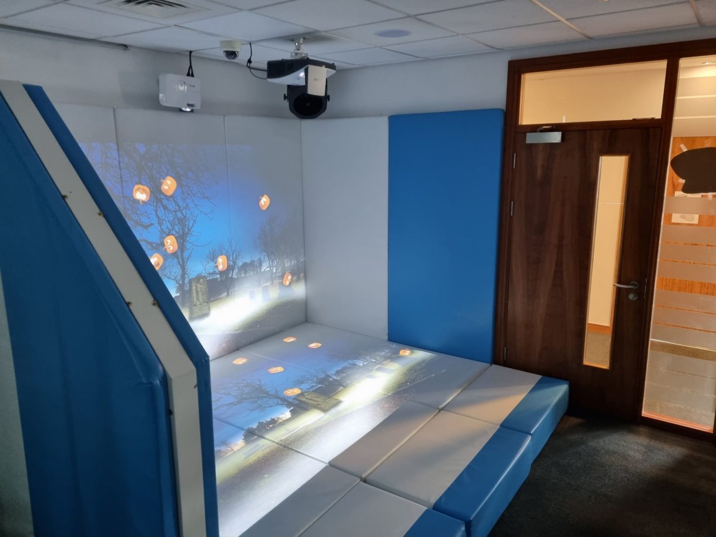 fully interactive immersive room including 2 interactive walls , 2 interactive floors and a range of DMX sensory effect hardware. displaying the pumpkin splat activity to provide physical stimulation in a SEND environment
