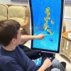 a man in a wheelchair interacting with fish on the screen