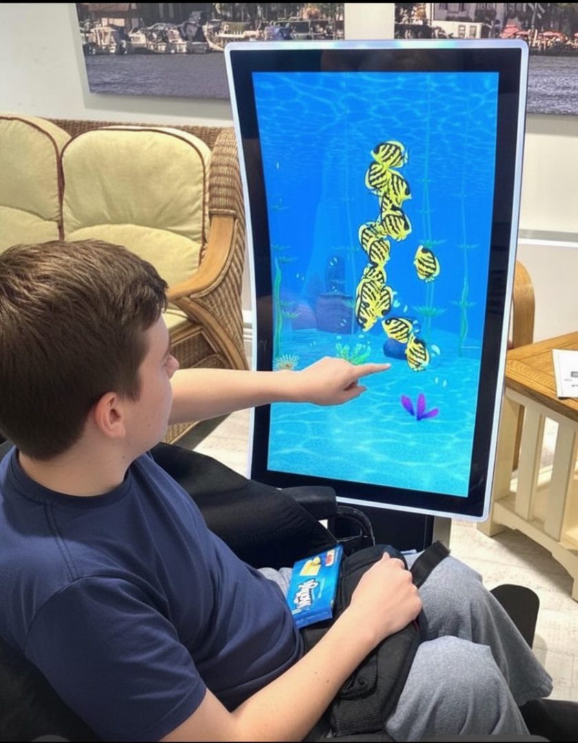 a man in a wheelchair interacting with fish on the screen
